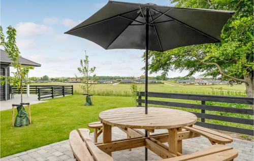 a wooden table with an umbrella on a patio at Lovely Home In Frederiksværk With Wifi in Frederiksværk