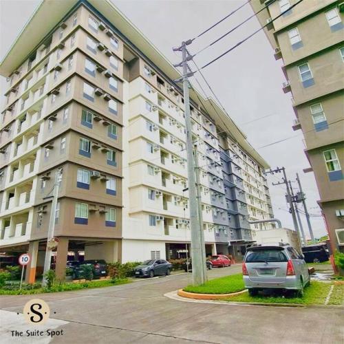 a large apartment building with a car parked in a parking lot at Condo in Las Piñas- The Suite Spot Alabang in Manila