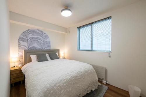 a bedroom with a white bed and a window at Nakajima Nouveau in Sapporo