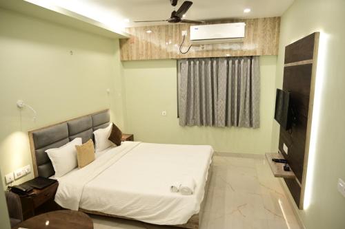 a bedroom with a large white bed and a flat screen tv at The Infigo in Beherāpāt