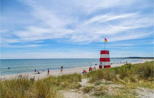 a red and white lighthouse on a beach with people at Lovely Home In Grenaa With Kitchen in Grenå