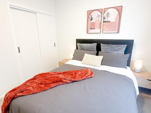 a bedroom with a bed with a red blanket on it at Modern 3Bdr 2bath Apartment Beach Golf Shops Relax in Paraparaumu Beach