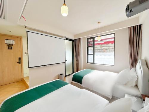 a hotel room with two beds and a projection screen at 西湖柒涧锦月民宿 Lakeside Moon Retreat in Hangzhou