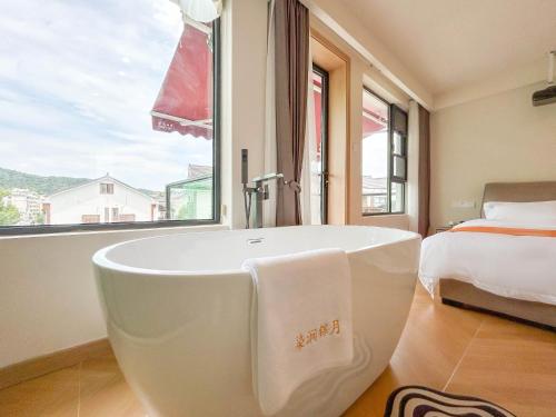 a white bath tub in a bedroom with a bed at 西湖柒涧锦月民宿 Lakeside Moon Retreat in Hangzhou