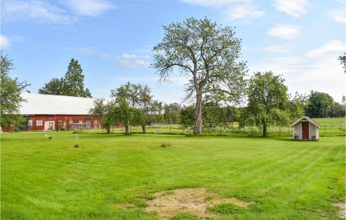 a large green field with a barn and a tree at Gorgeous Home In Braås With Kitchen in Braås