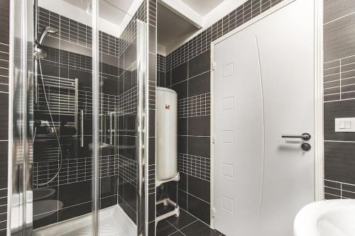 La salle de bains est pourvue de carrelage noir, d'une douche et d'un lavabo. dans l'établissement Imperial plazza, à Menton