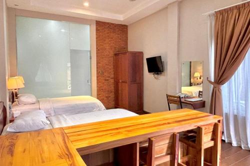 a bedroom with two beds and a desk and a television at Thong's Inn Hotel Kualanamu in Medan