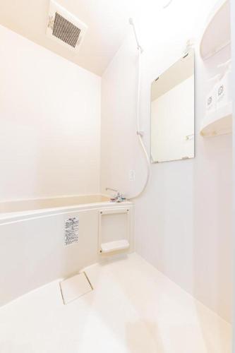 a white bathroom with a mirror and a sink at JA Hotel Shinfukae in Osaka