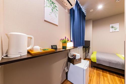 a room with a bed and a counter with a coffee maker at JA Hotel Shinfukae in Osaka