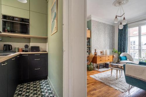 Il comprend une cuisine et un salon avec des murs verts. dans l'établissement Appartement charmant à Paris 31 m² avec équipements modernes, à Paris