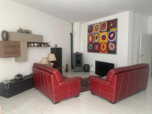 a living room with two red chairs and a television at B&B Passione Salento in Surbo