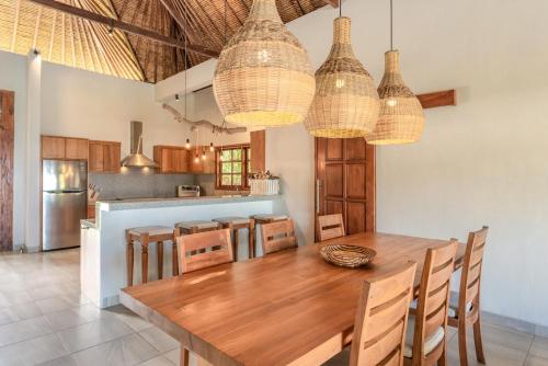 una cucina con un tavolo di legno e alcuni lampadari di Villa Emerald a Banjar