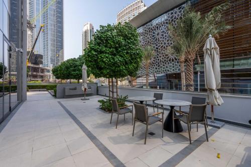 a patio with tables and chairs and trees at GuestReady - Elegant 1BR l Premium Amenities in Dubai