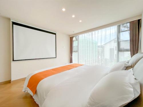 a bedroom with a large white bed with a large window at 西湖柒涧锦月民宿 Lakeside Moon Retreat in Hangzhou