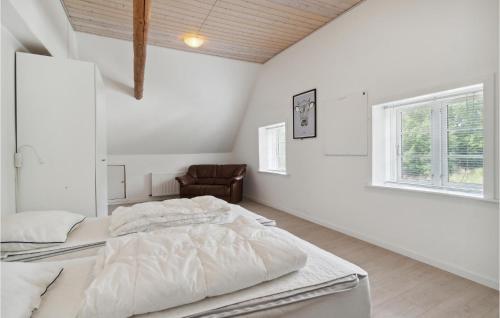 a white bedroom with a bed and a chair at Markeregaard in Spidsegård