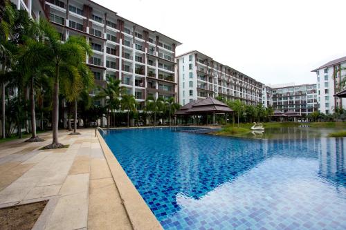 a large swimming pool in front of a building at Ratchy Condo in Bang Sare