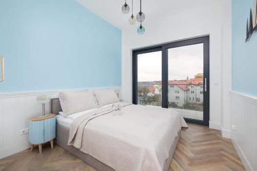 Un dormitorio blanco con una cama y una ventana grande. en Prestiżowy Apartament Baltic Sand 300 m od Plaży Mrzeżyno by Noclegi Renters, en Mrzeżyno