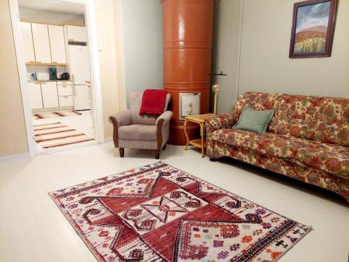 a living room with a couch and a chair and a rug at Taideniityn huoneisto Tuuli 1-4lle in Varkaus