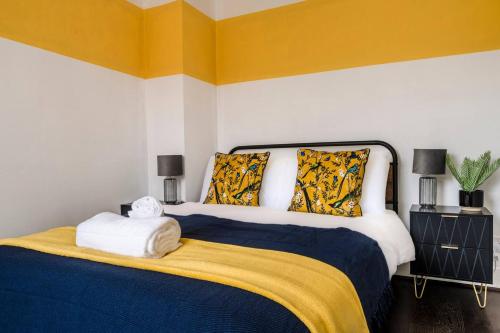 a bedroom with a large bed with yellow and white walls at Comfortable 3 Bedroom Terraced Home, Sleeps 5, Monthly Extended Stays in Northampton