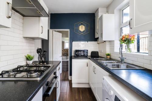 a kitchen with white cabinets and black counter tops at Comfortable 3 Bedroom Terraced Home, Sleeps 5, Monthly Extended Stays in Northampton