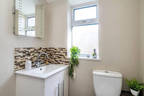 a bathroom with a sink and a toilet and a window at Comfortable 3 Bedroom Terraced Home, Sleeps 5, Monthly Extended Stays in Northampton