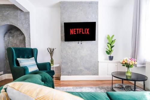 a living room with a green couch and a tv at Comfortable 3 Bedroom Terraced Home, Sleeps 5, Monthly Extended Stays in Northampton