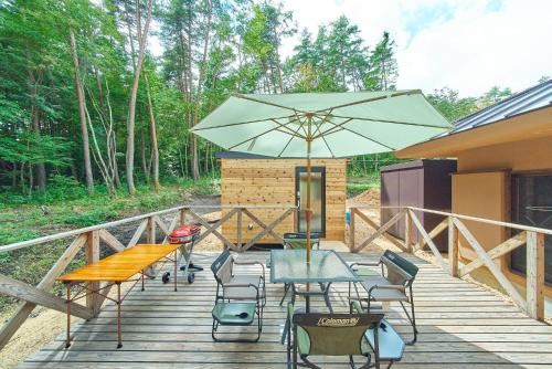 a patio with a table and chairs and an umbrella at Azumino Komorebi - 安曇野こもれび - in Azumino