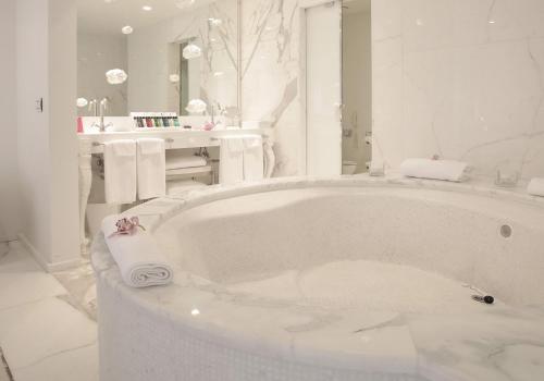 a white bathroom with a tub and a sink at Boscolo Nice Hotel & Spa in Nice