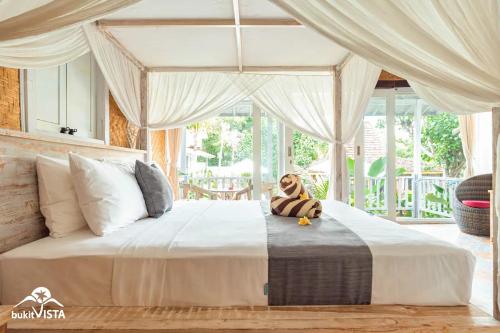 a large bed with a stuffed animal sitting on top of it at D'Pendem Cottage's by Bukit Vista in Uluwatu