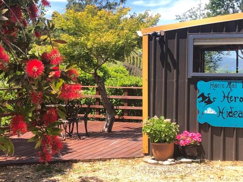 a deck with flowers and a sign next to a building at Heron Hideaway at First Light Rangihaeata Retreat in Rangihaeata