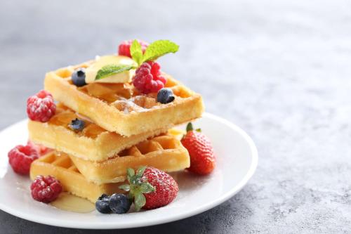 a stack of waffles with berries on a plate at Hilton Houston Plaza/Medical Center in Houston