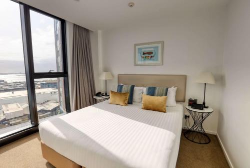a bedroom with a large bed and a large window at Ramada Suites By Wyndham Victoria Street West in Auckland