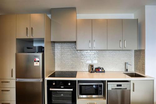 a kitchen with stainless steel appliances and white cabinets at Ramada Suites By Wyndham Victoria Street West in Auckland