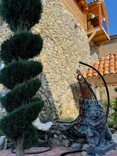 a statue of a lion sitting next to a tree at Davitiani in Tʼelavi