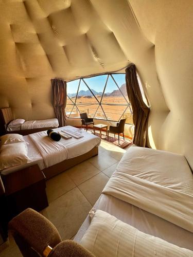 a bedroom with two beds and a large window at Rum Angel Camp in Wadi Rum