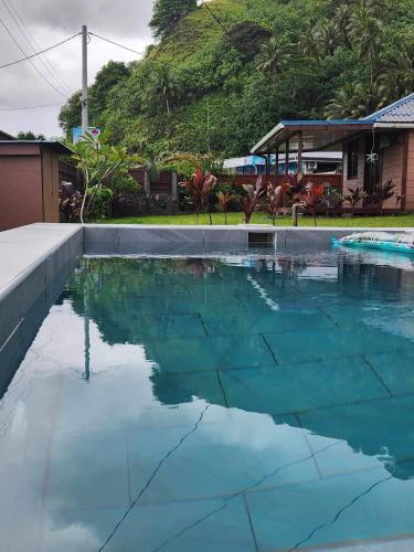 una piscina con agua azul frente a una casa en Te Ika Nui Lodge, en Faaone