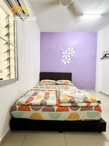 a bed in a room with a purple wall at Harmony Stay Ujung Pasir By Nestcove in Melaka