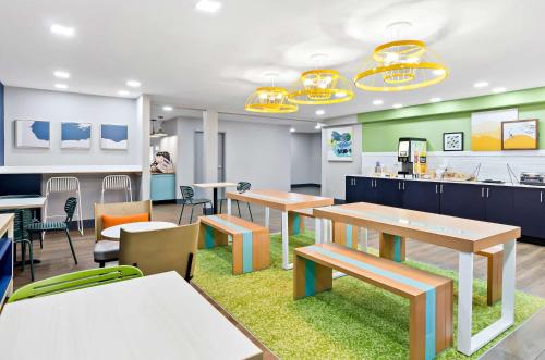 a cafeteria with tables and chairs and a kitchen at Spark by Hilton Winston-Salem University in Winston-Salem