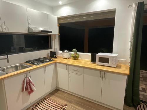 a kitchen with white cabinets and a microwave on a counter at Tepoea Lodge in Fare