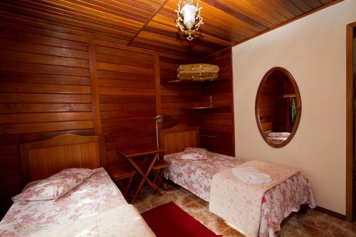 サン・トメー・ダス・レトラスにあるBosque dos Beija-Flores Pousada e Spaのベッドが2つと鏡がある部屋