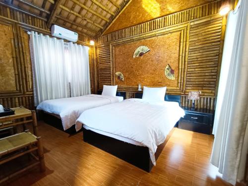 a bedroom with two beds with white sheets at Tam Coc Sunshine Homestay in Ninh Binh