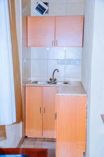 a small kitchen with a sink and wooden cabinets at Kigali diplomat Hotel in Kigali