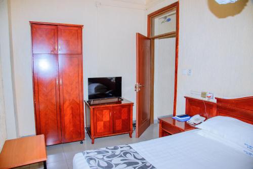 キガリにあるKigali diplomat Hotelのベッドルーム1室(ベッド1台、キャビネット内のテレビ付)