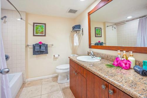 a bathroom with a sink and a toilet and a mirror at Islander on the Beach 154 in Kapaa