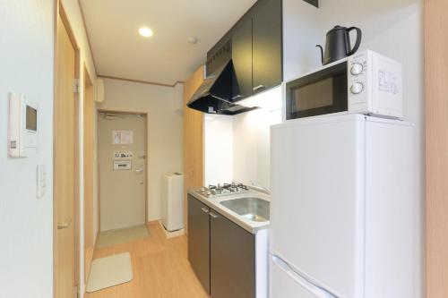 a kitchen with a white refrigerator and a sink at Domire Setagaya by Tranova in Tokyo
