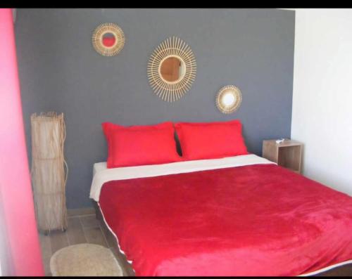 a bedroom with a red bed with two mirrors on the wall at Le Longani 974 in Saint-Pierre
