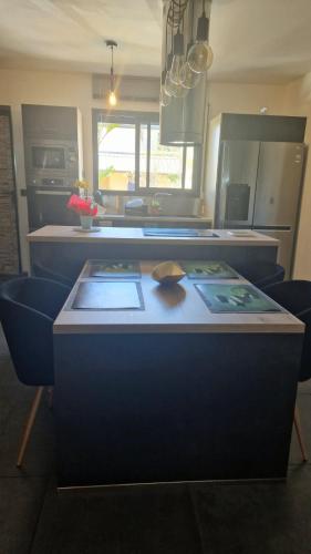 a kitchen with a counter with blue chairs and a table at Le Longani 974 in Saint-Pierre