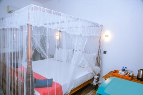a bedroom with a canopy bed with white curtains at Surf Sea Breeze in Mirissa