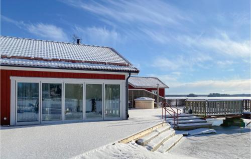 a red house with snow on the ground and a deck at Stunning Home In Tingsryd With Wifi in Tingsryd
