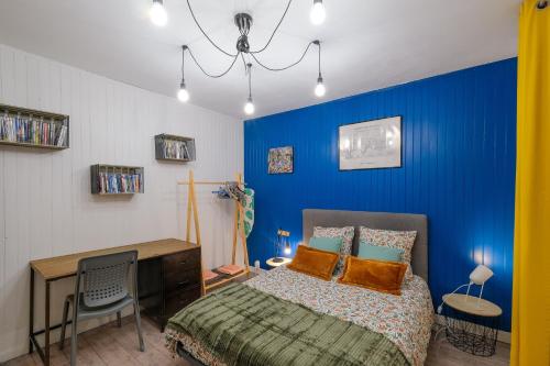 - une chambre avec des murs bleus, un lit et un bureau dans l'établissement La terrasse de M.Hulot - 1 chambre, à Saint-Nazaire